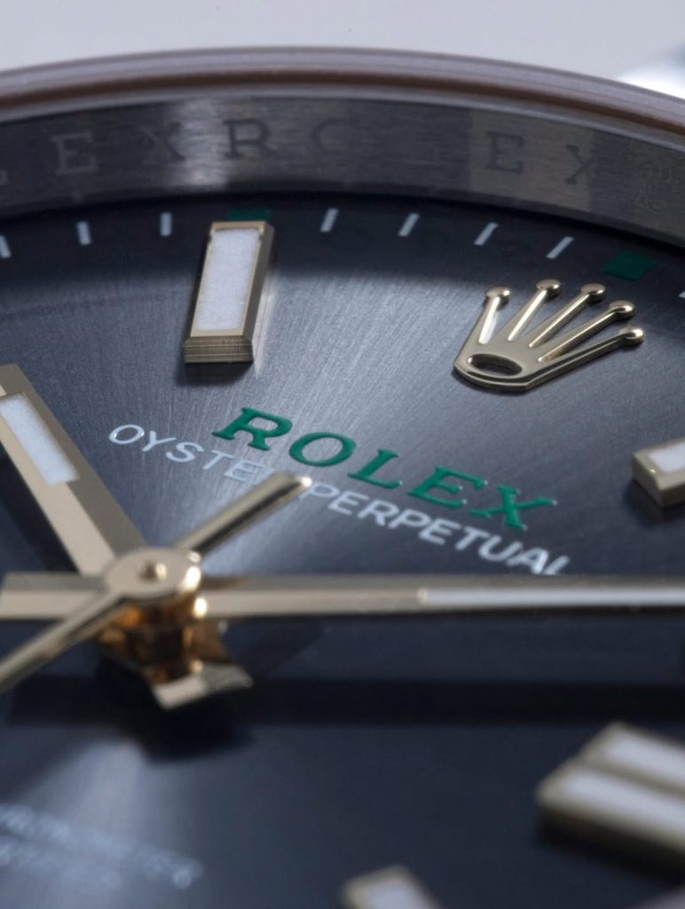 High-magnification capture of the green text accent and 3D applied crown logo at 12 o'clock.